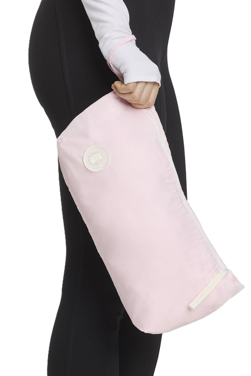 Person holding pink bag with white valve, against black pants.