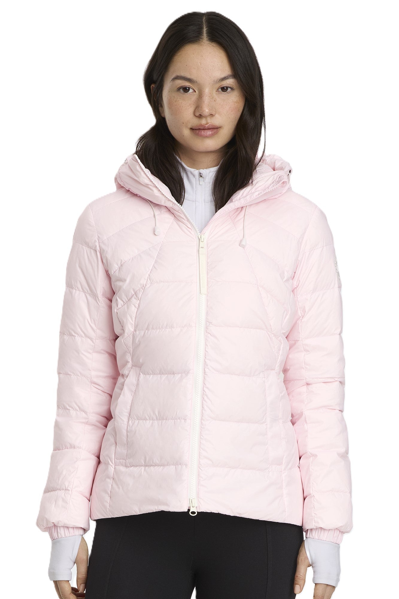 A woman wearing a light pink hooded puffer jacket with a white zipper.