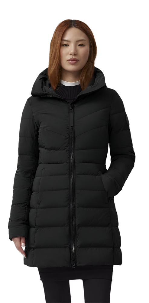 A woman in a black mid-length parka with a hood and zippered front.