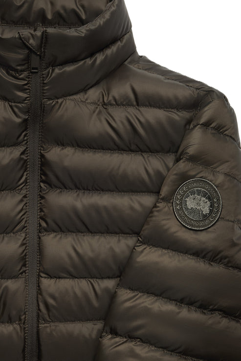 Close-up of a dark olive down puffer jacket with visible zipper and circular brand patch on the sleeve.