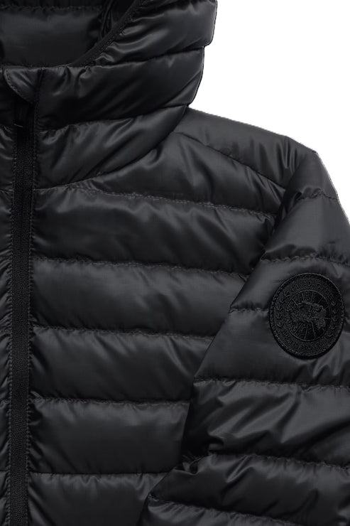 Close-up of a black hooded puffer jacket featuring a circular black badge on the sleeve.