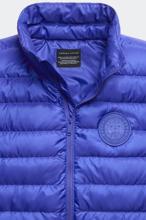 Close-up of a blue puffer vest with a zipper closure and a circular patch on the chest.