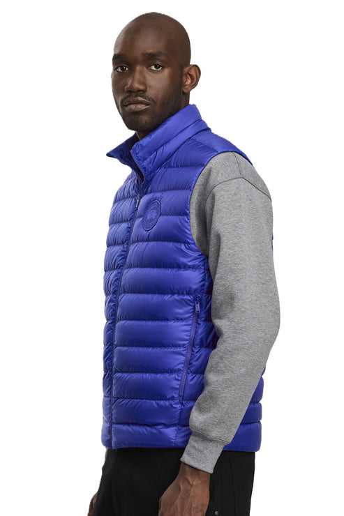 A person wearing a shiny, royal blue puffer vest over a gray long-sleeved shirt.