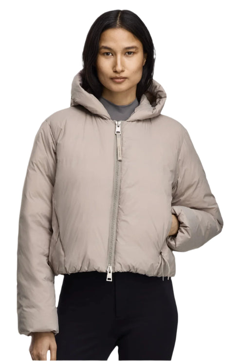 A tan-colored puffer jacket with a hood, zippered closure, and drawstring waist, worn by a model.