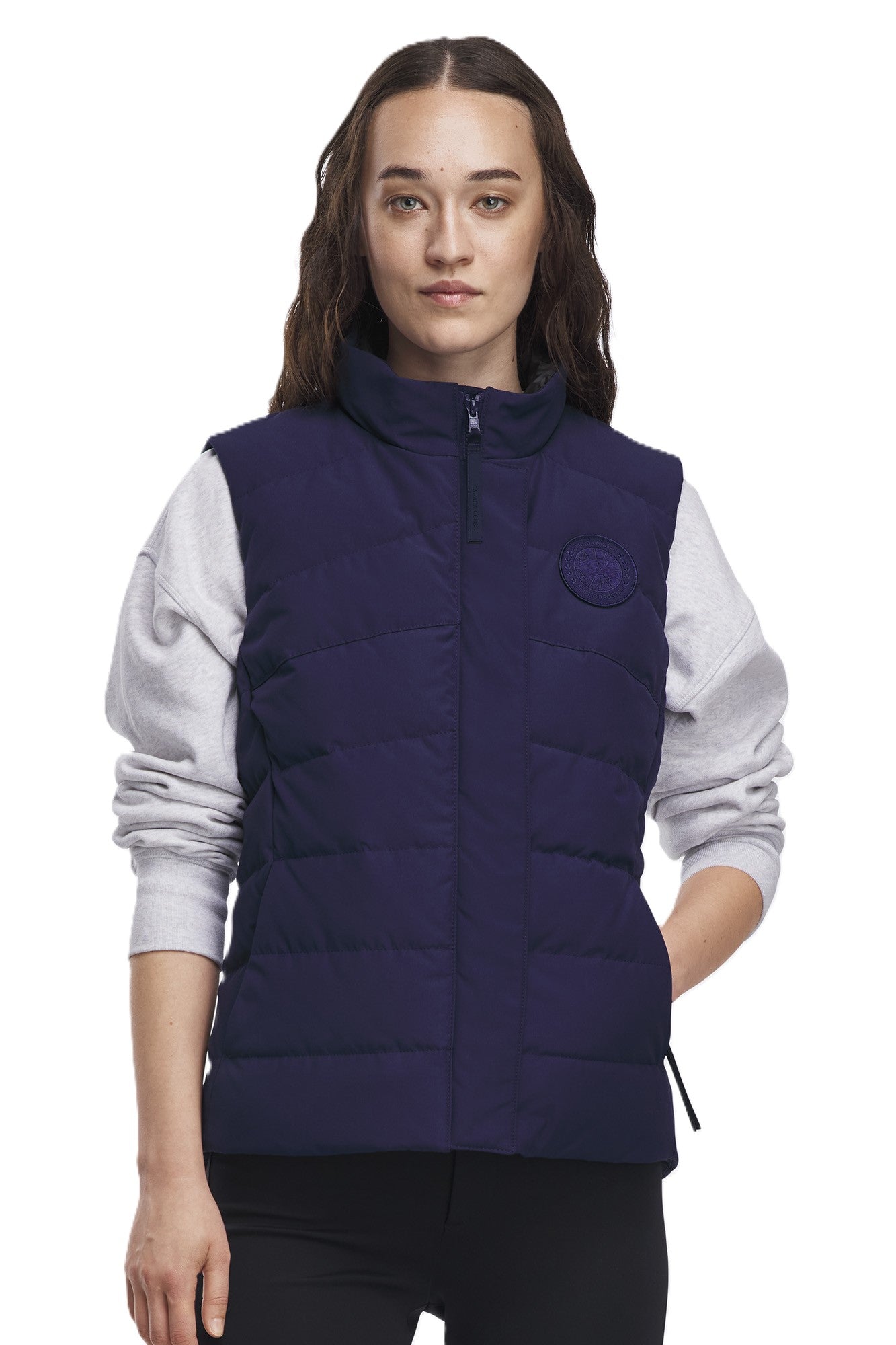 A woman wears a sleeveless, quilted navy vest.