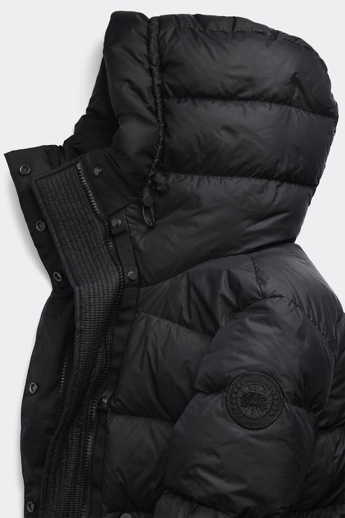Close-up of a black puffer jacket featuring a hood and a circular logo patch.