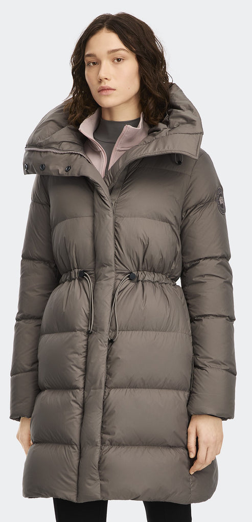 A woman wearing a brown puffer jacket with a high collar.