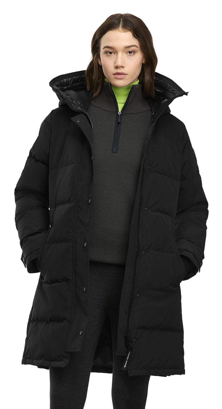 A woman wearing a long black down jacket with a hood.