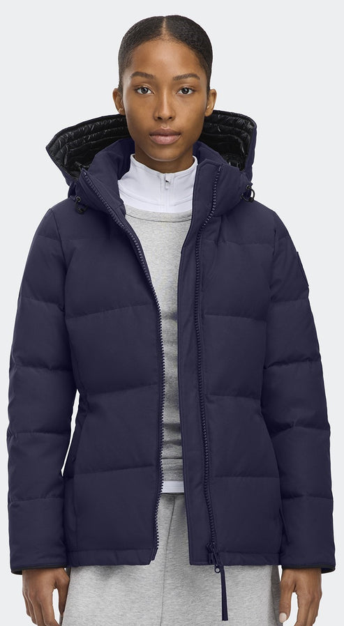 A woman wearing a navy blue puffer jacket with a hood and gray fur trim.
