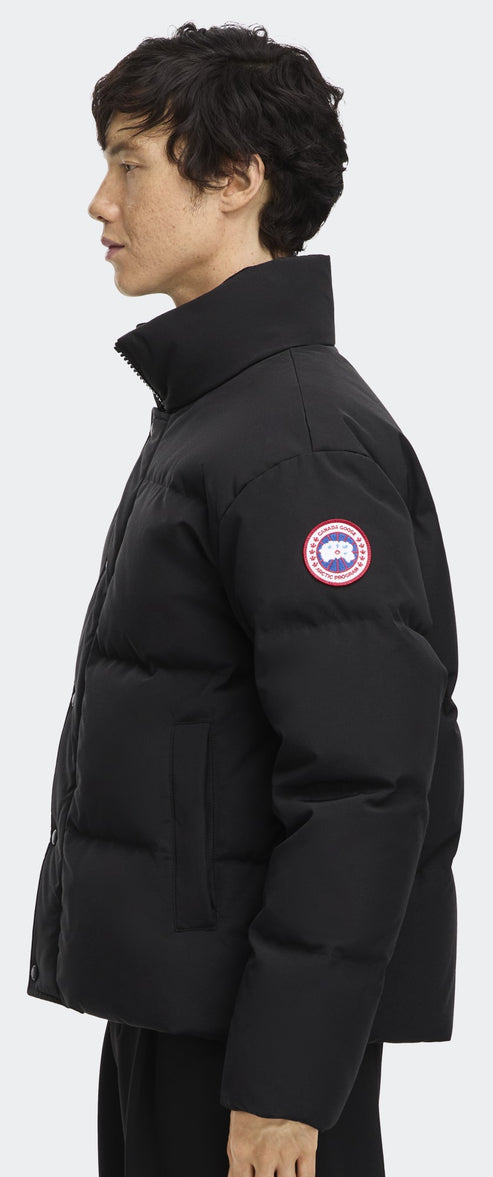 A person in a black, puffy jacket with a logo patch on the arm.