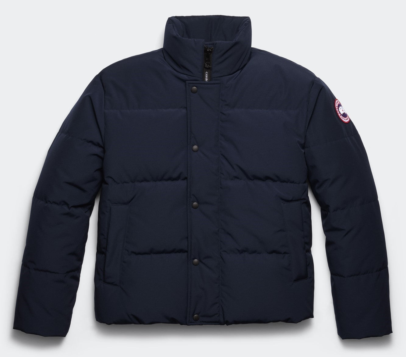 Navy blue puffer jacket with snap closure and circular logo on the sleeve.