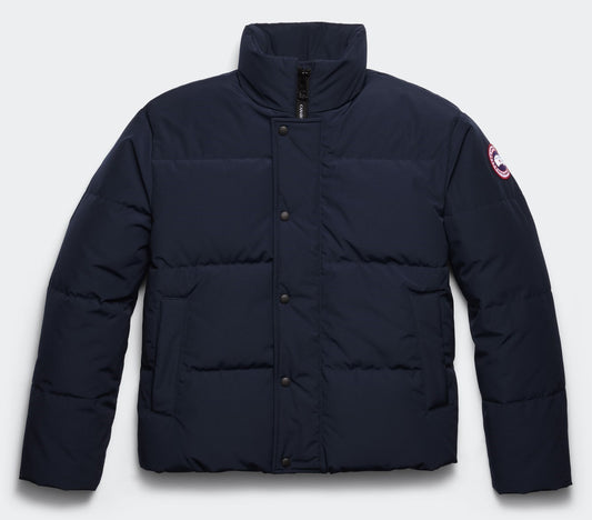 Navy blue puffer jacket with snap closure and circular logo on the sleeve.