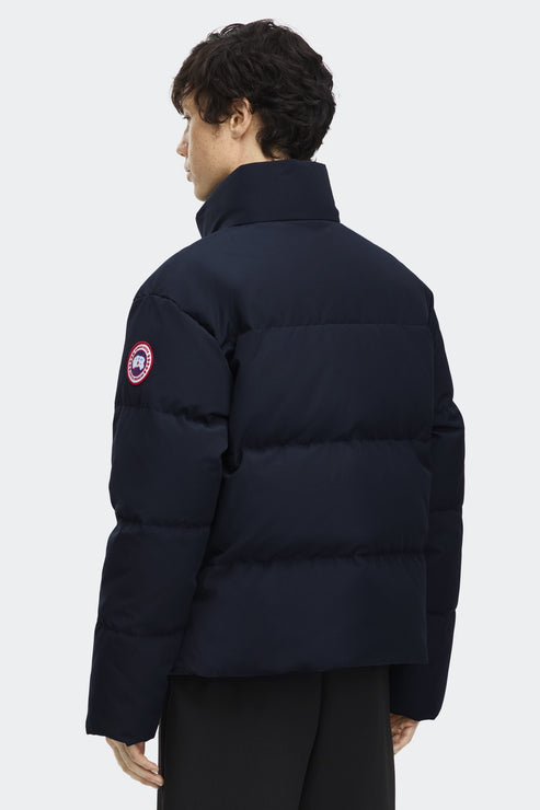 Dark blue puffer jacket with a circular badge on the left sleeve.
