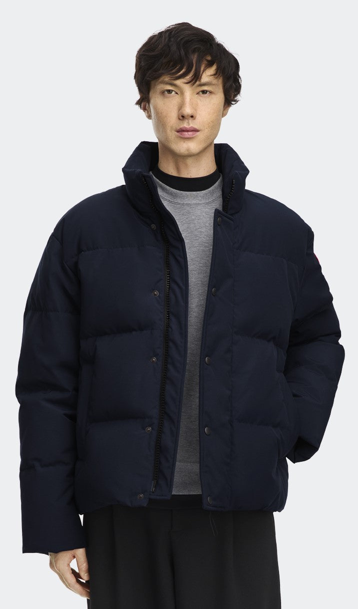 A man in a navy blue puffer jacket with a high collar and dark pants.