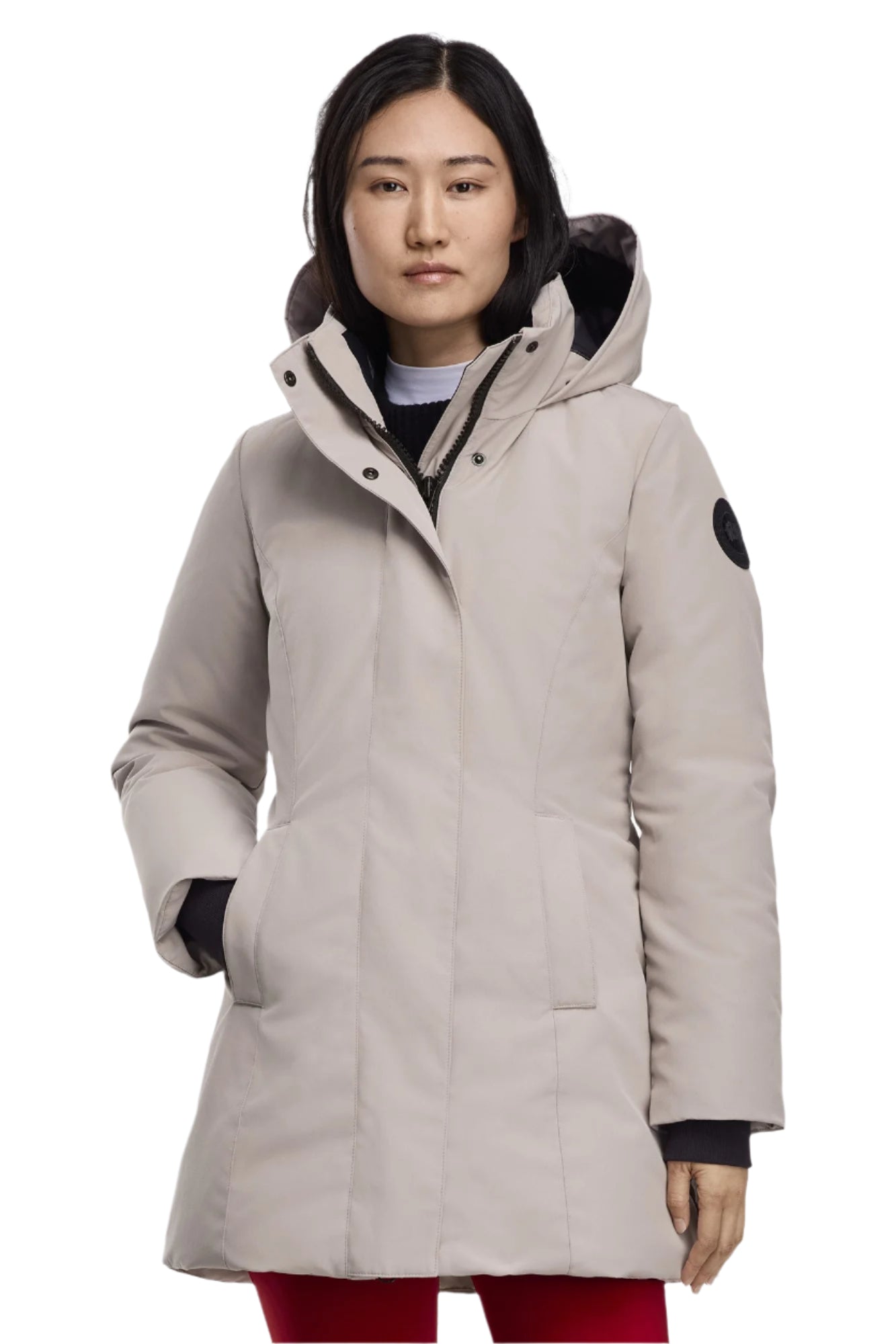 A woman wearing a knee-length tan parka with a fur-lined hood.