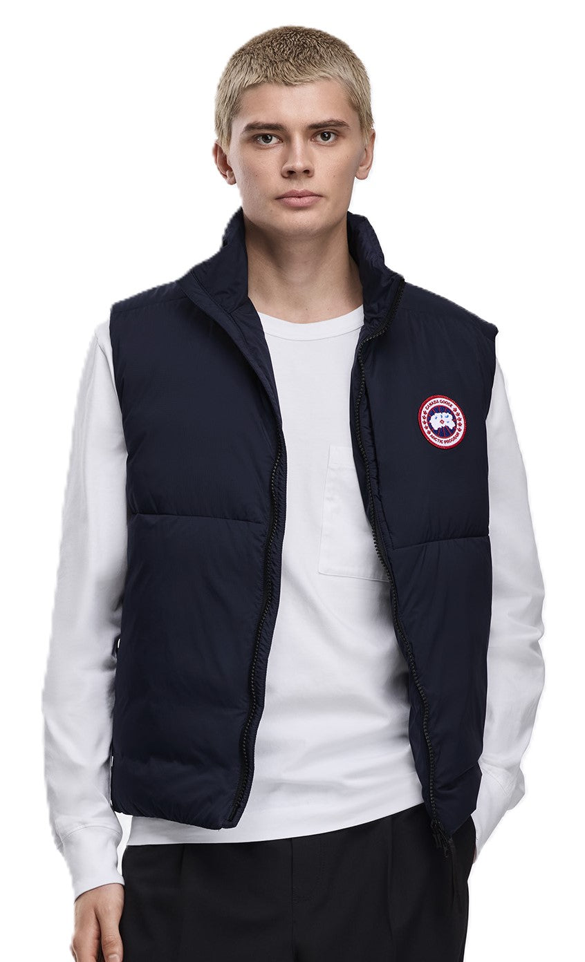 A man in a navy blue puffer vest over a white shirt.