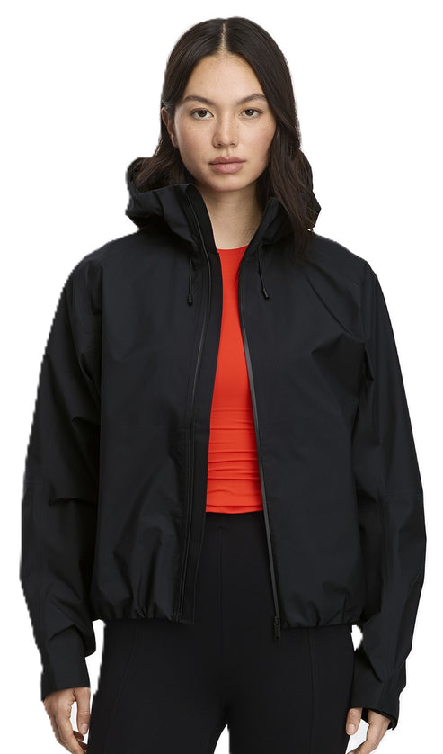A woman in a black, hooded windbreaker and red shirt.