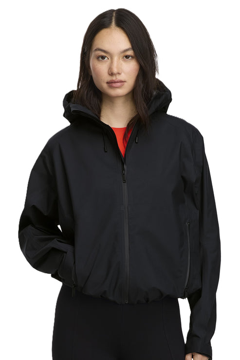 A woman in a black zip-up hooded jacket with an elastic hem.
