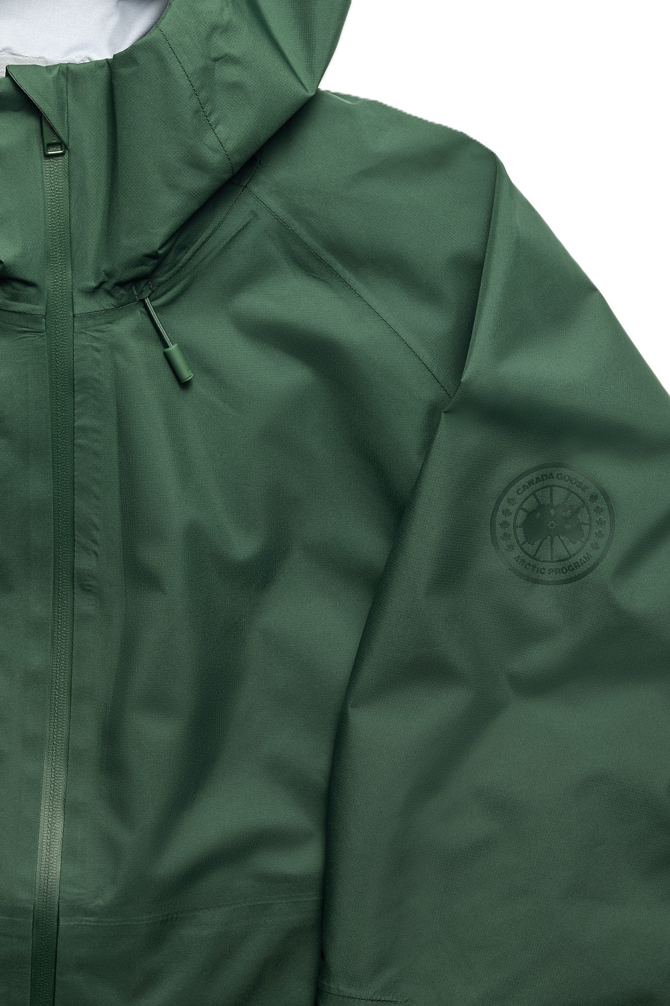 Close up of a dark green, rainproof hooded jacket with a zipper.