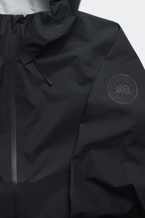Close up of a black jacket, featuring a black circular logo on the upper sleeve.