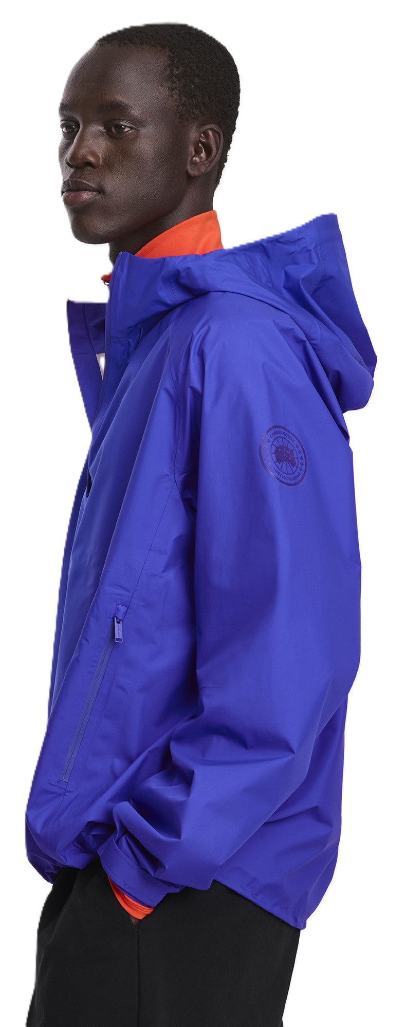 A person wearing a blue hooded jacket over an orange collared shirt.