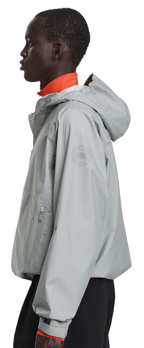 A person wearing a gray jacket with a hood and an orange undershirt.