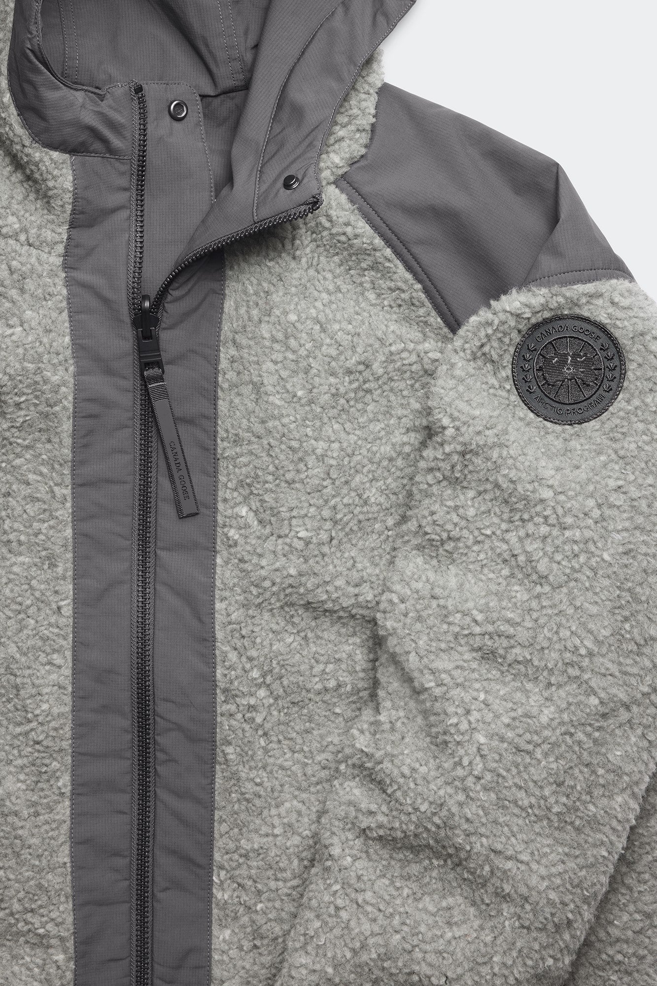 Gray sherpa jacket with dark gray accents and round logo patch on the sleeve.