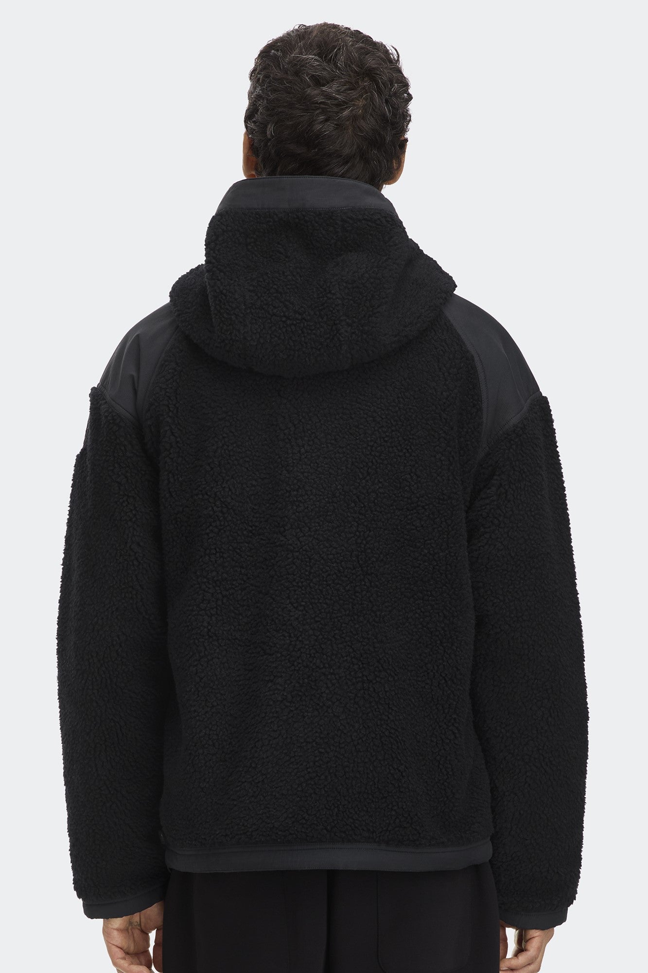 Black sherpa hooded jacket with shoulder panels viewed from behind.