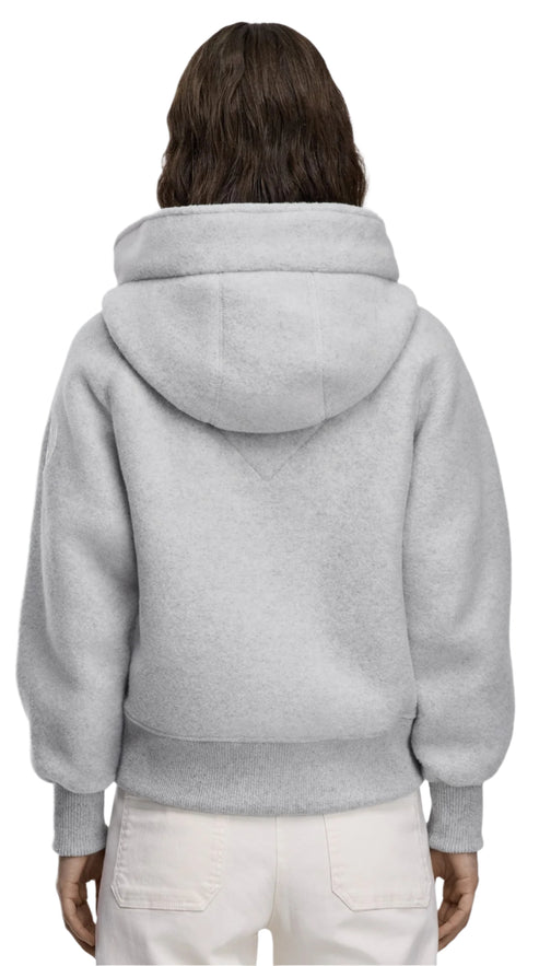 Back view of a person wearing a gray, furry hoodie with cuffed sleeves and white pants.