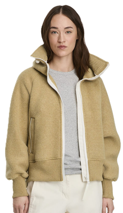 A woman models a beige wool jacket with a white zipper and collar.