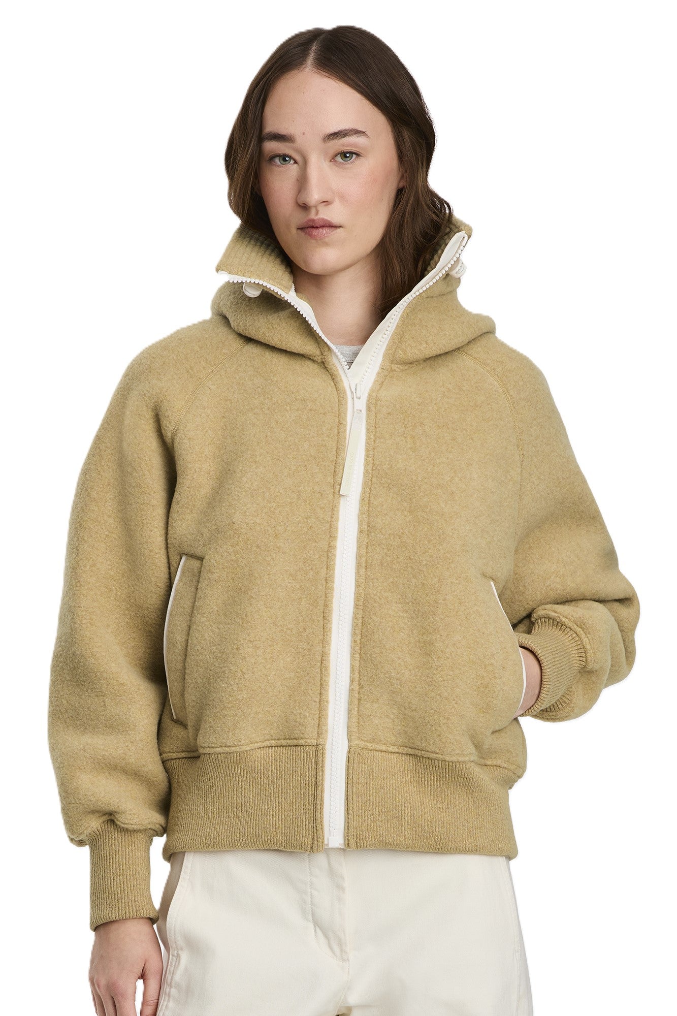 A woman models a tan, fleece, hooded jacket with a white zipper and trim.
