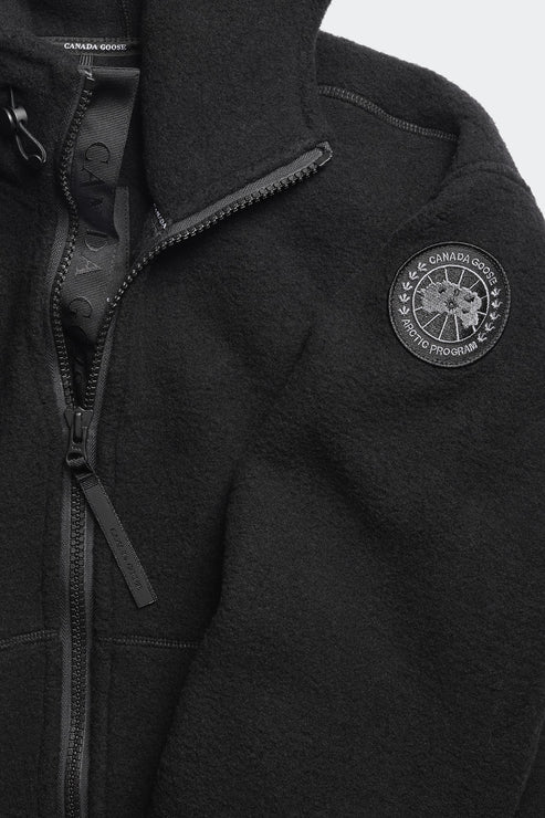 Close-up of a black fleece jacket with a zipper, collar, and circular logo on the right chest.