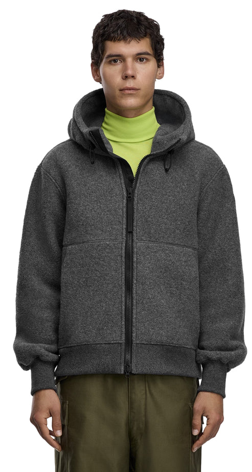 A man in a gray fleece hoodie with a zipper and a neon green turtleneck sweater, and army green pants.