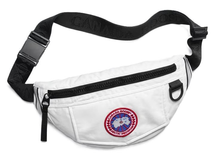 White fanny pack with a black zipper, adjustable black strap with repeating white text, and a circular logo with red lettering and a map of the arctic region.