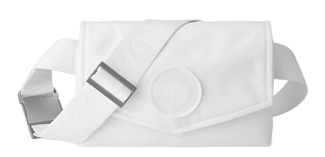 A white fanny pack with adjustable strap and a large round decorative medallion.