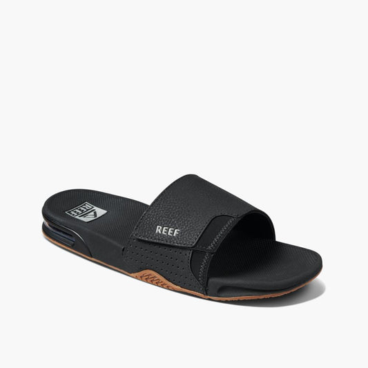 Black slide sandal with a padded strap that says REEF.
