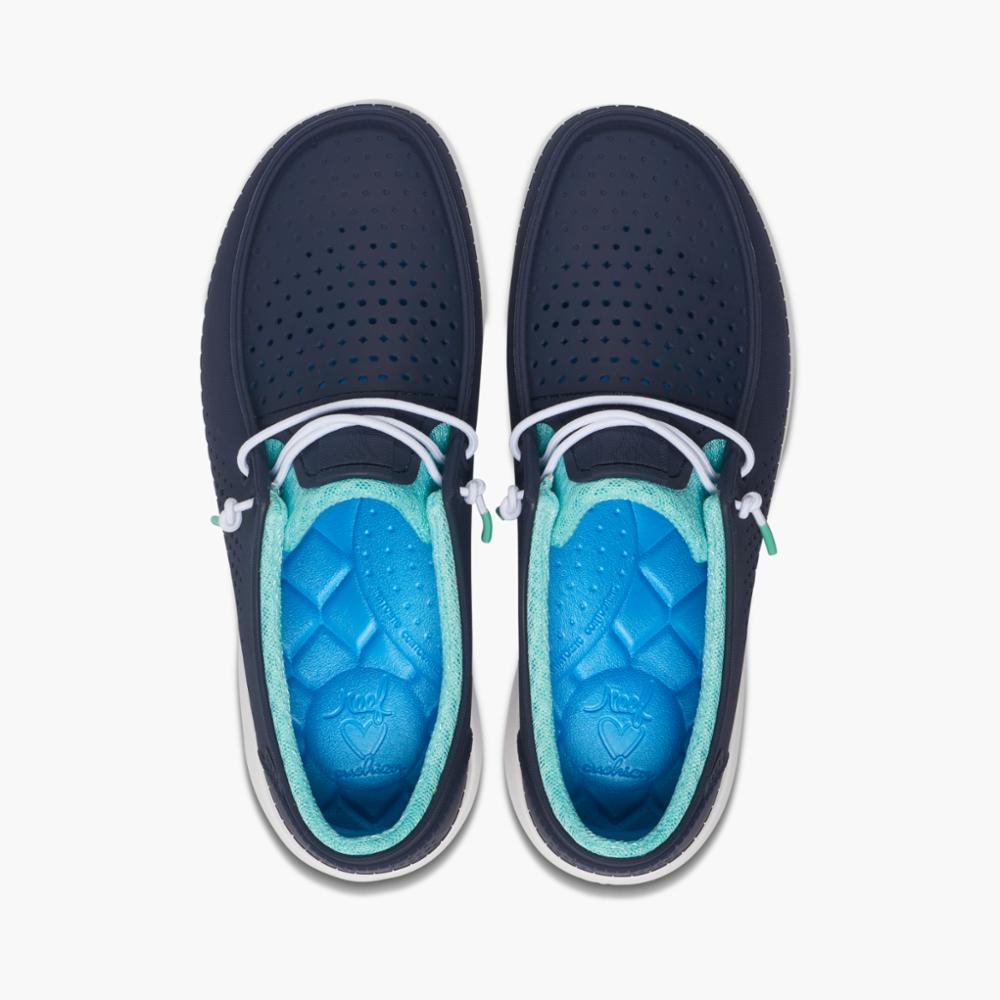 Overhead view of navy blue slip-on shoes with decorative white laces and blue molded insoles with teal trim.