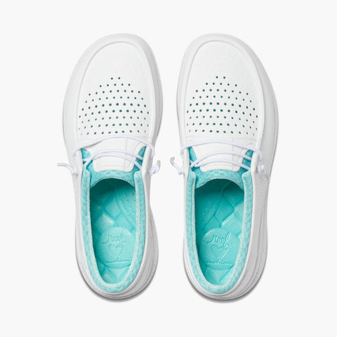 A pair of white slip-on shoes with round perforations on the top and a light-blue insole.