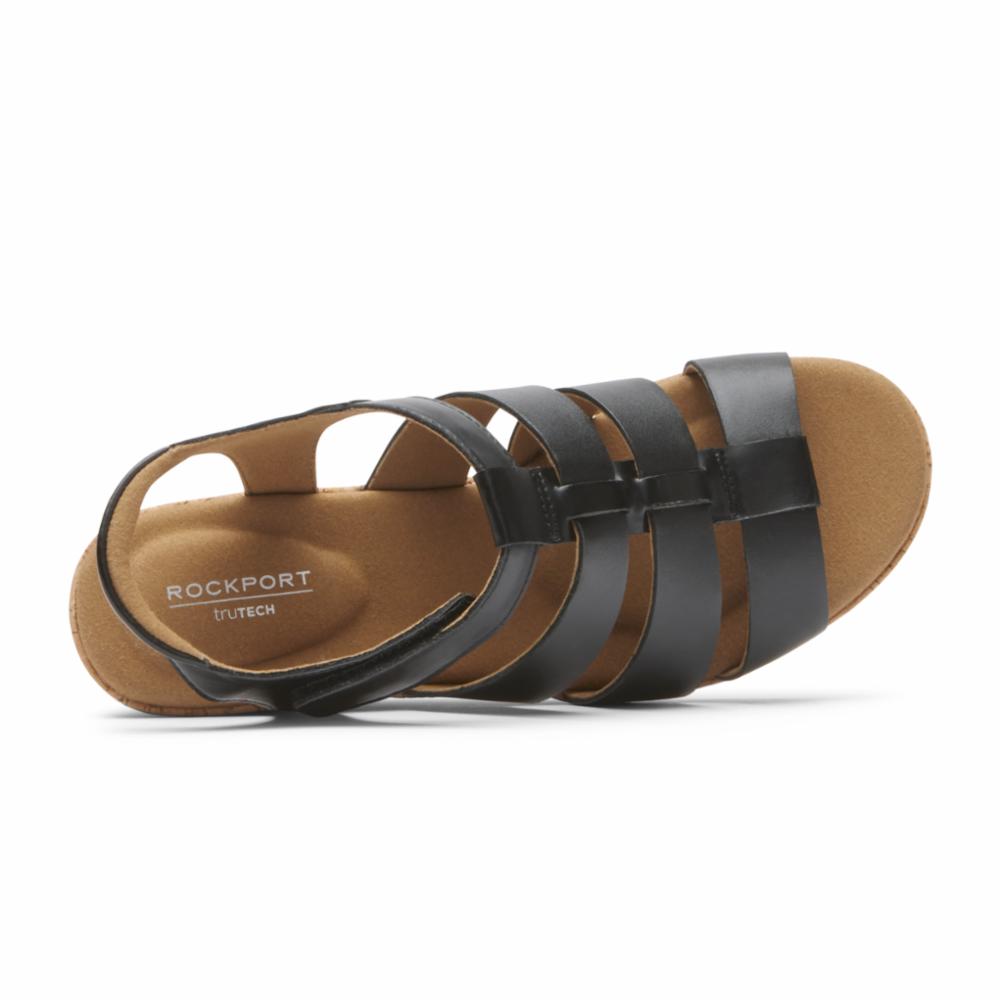 Close-up of a black leather sandal with multiple horizontal straps and a slingback, revealing the lightly cushioned insole and the text "ROCKPORT TRUTECH".