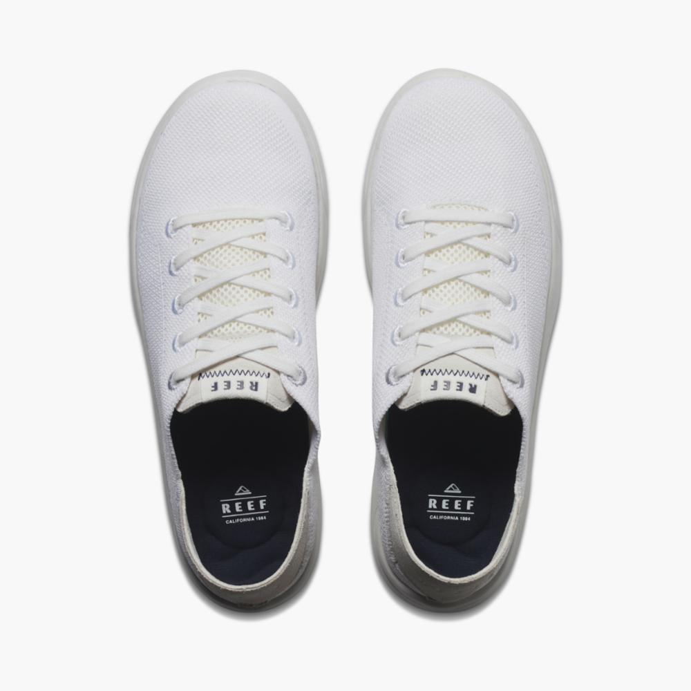 Overhead view of two white sneakers with laces; REEF logo on insole.