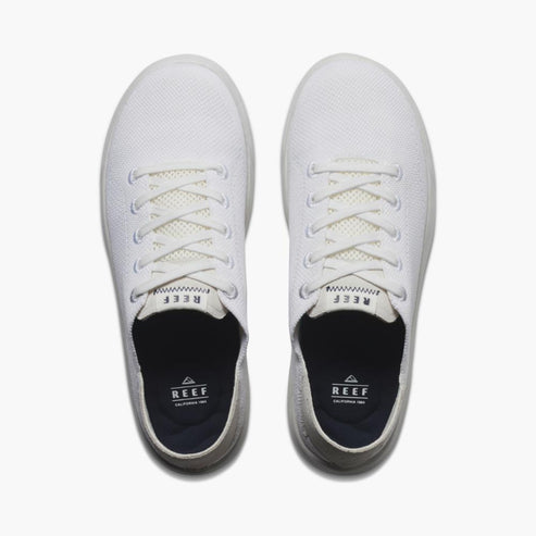 Overhead view of two white sneakers with laces; REEF logo on insole.