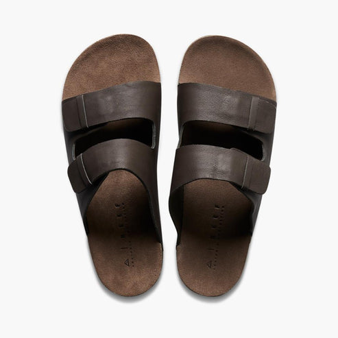 Pair of brown two-strap slide sandals with adjustable buckle.