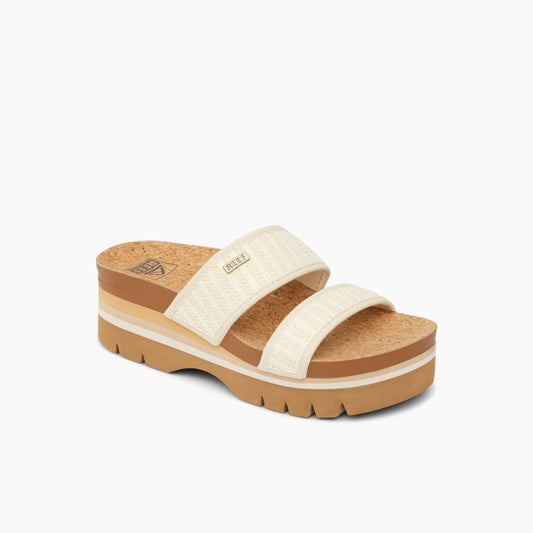 Beige sandal with two textured straps and a thick, striped platform sole.