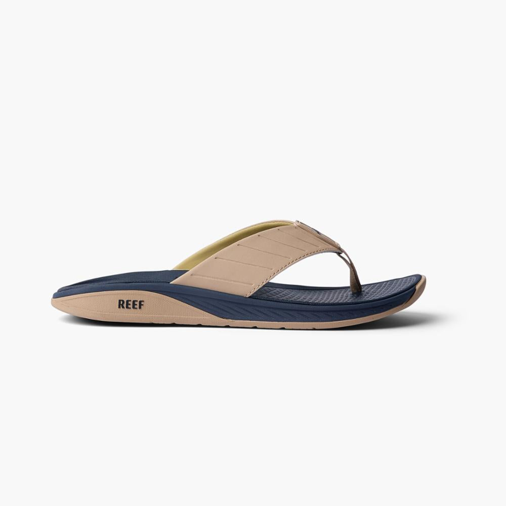 Side view of a beige sandal with a navy footbed and "REEF" printed on the side.