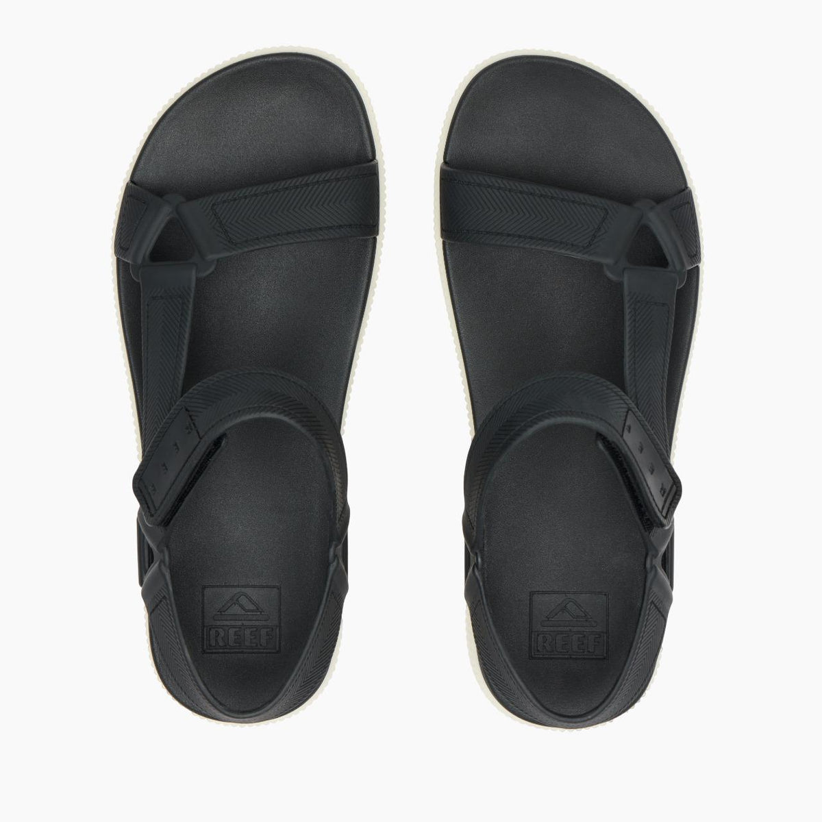 Overhead view of a pair of sandals: Black footbed and straps with an embossed square logo near the heel.