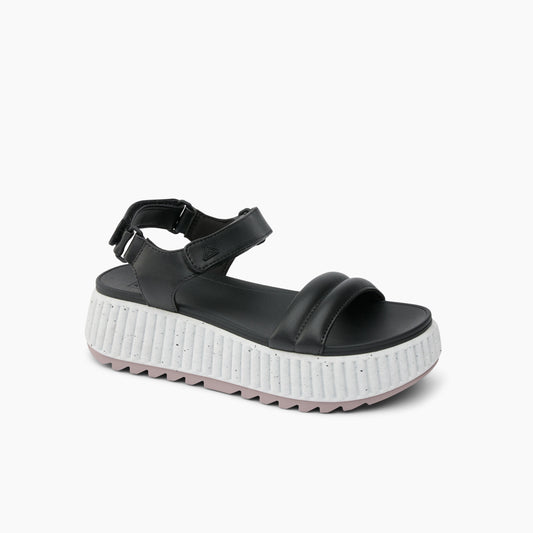 Black platform sandal with velcro ankle strap and thick white sole.