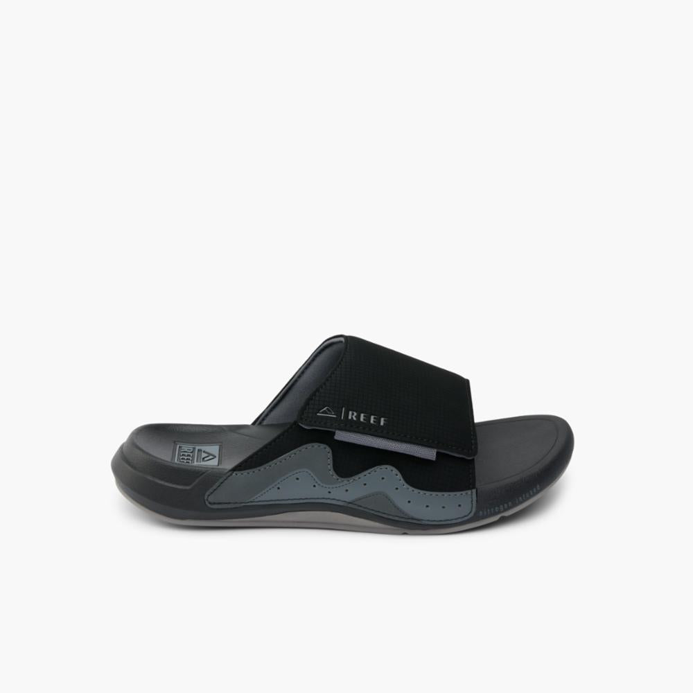 Black slide sandal with fabric upper strap and wavy design.