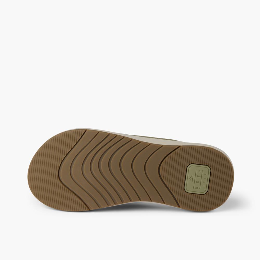 The underside of a green sandal with tan treads.