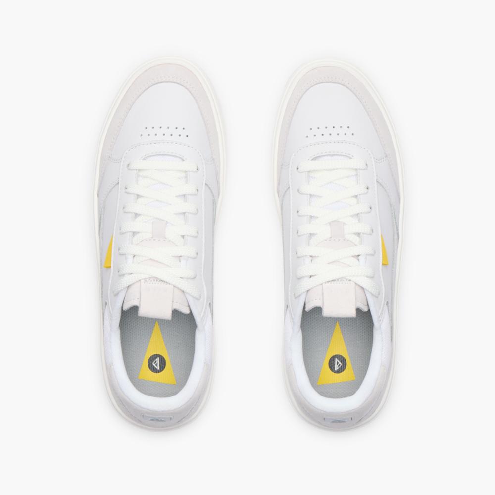 A pair of white tennis shoes with a yellow triangle on the insole.
