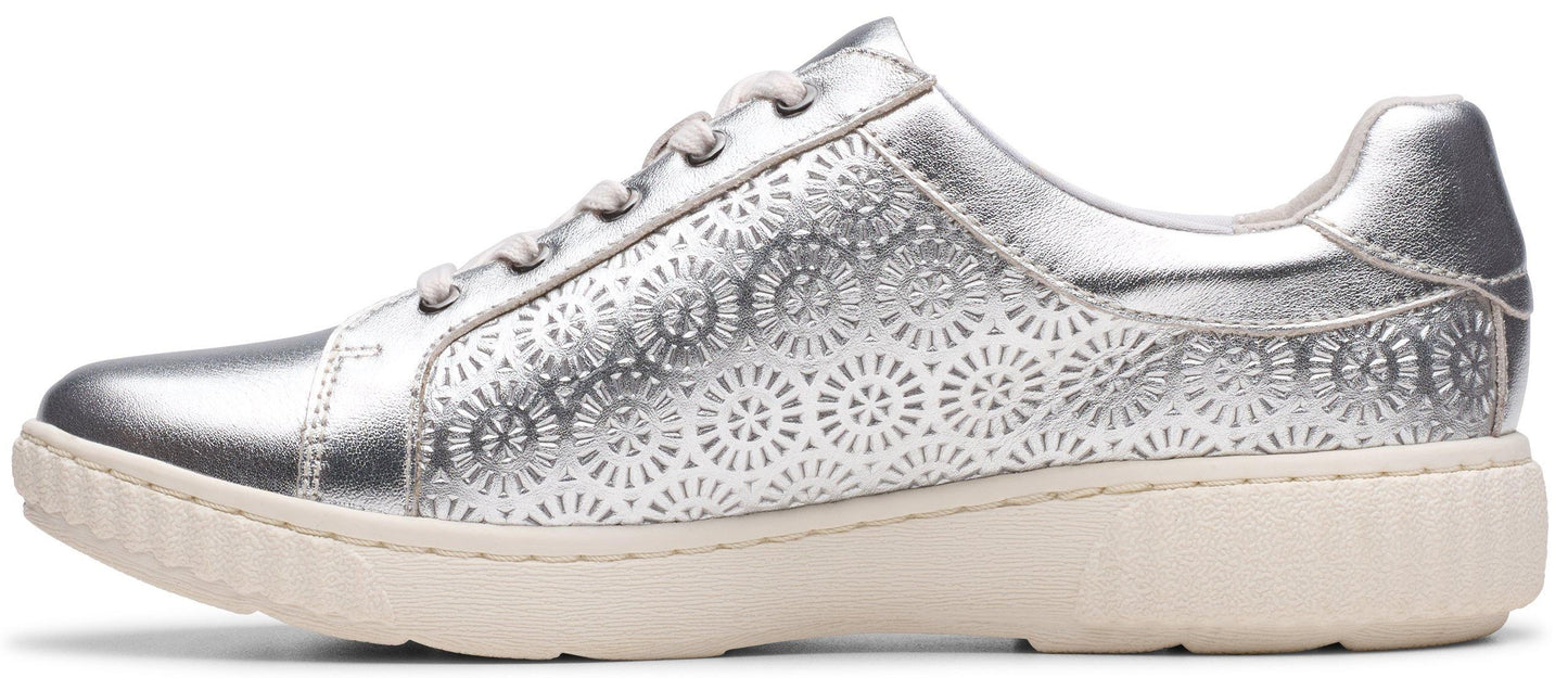A silver women's sneaker with a lace-up closure and floral cutouts.